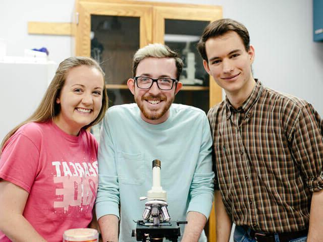 Three students with microscope